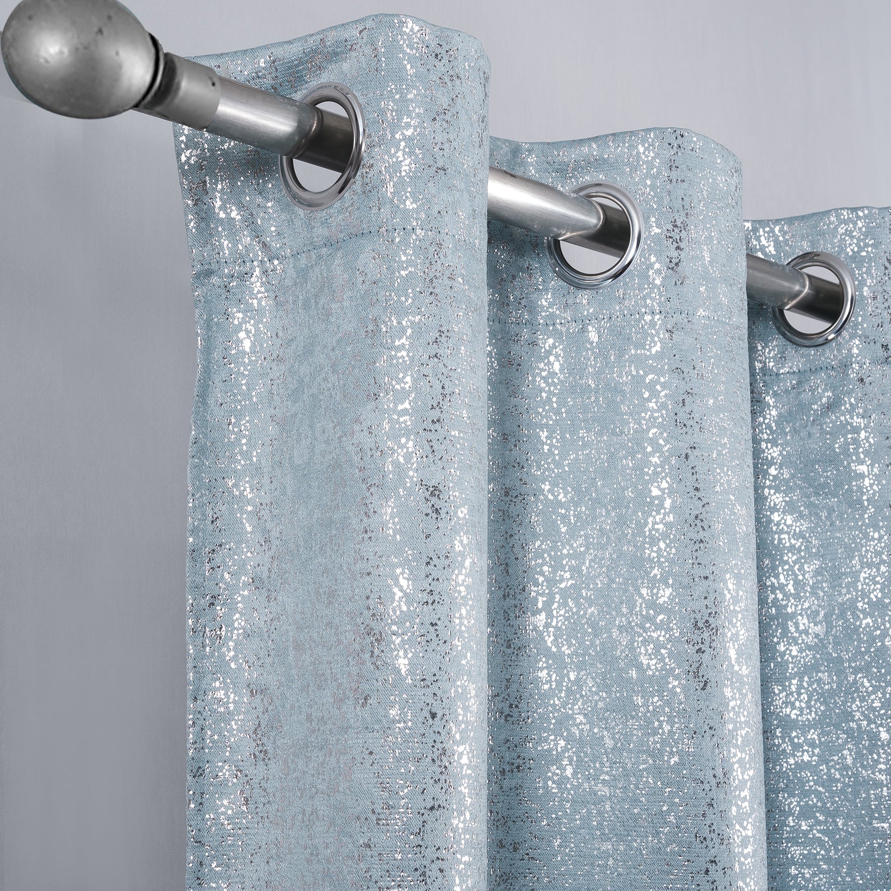 Baby Blue Glittery curtain with silver grommets on a gray background