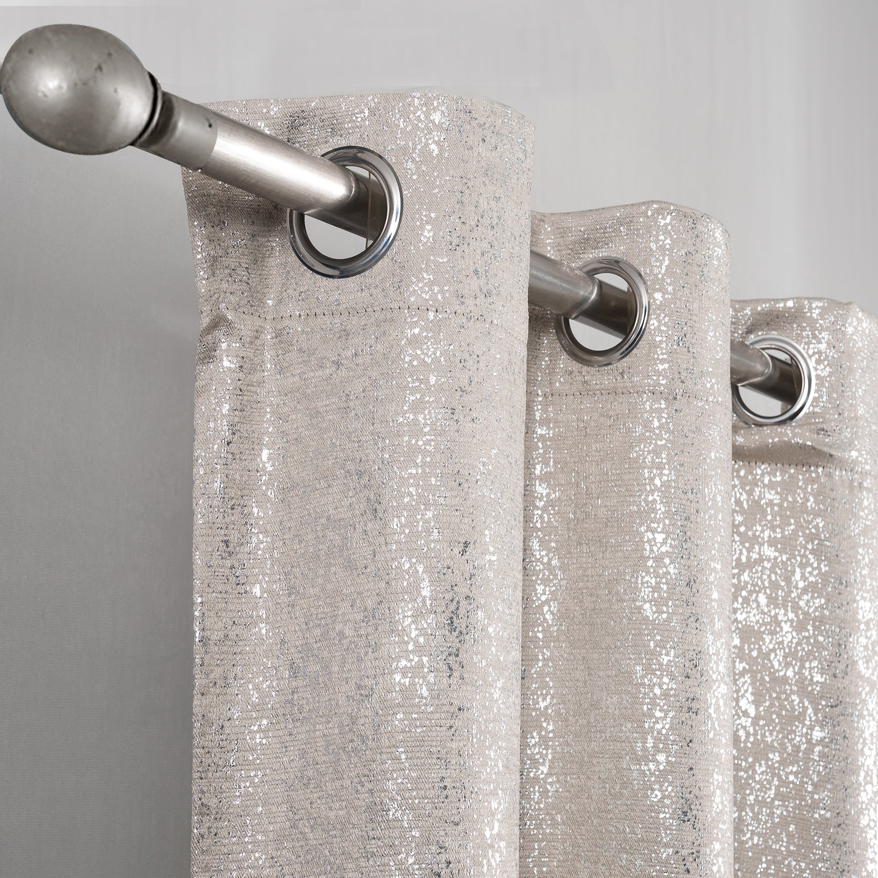 Beige Glittery curtain with silver grommets on a gray background