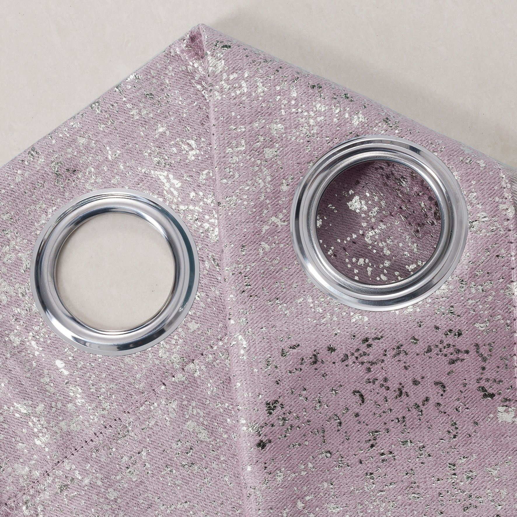 Close-up of a pink glittery curtains with two silver grommets.
